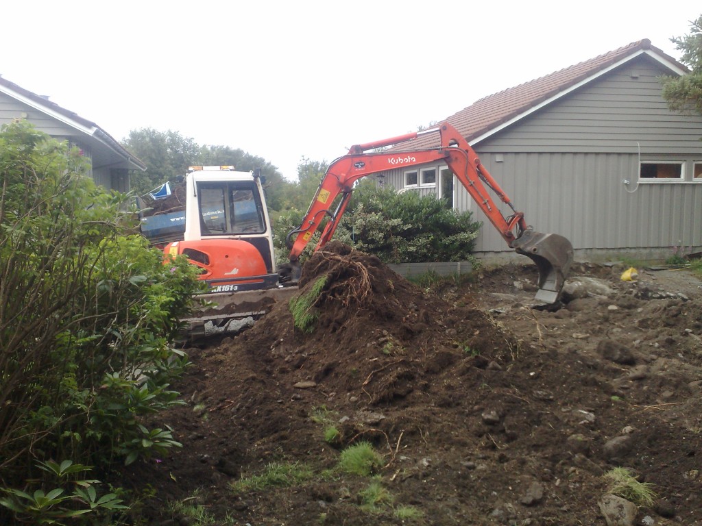 gravemaskin i hagen som graver